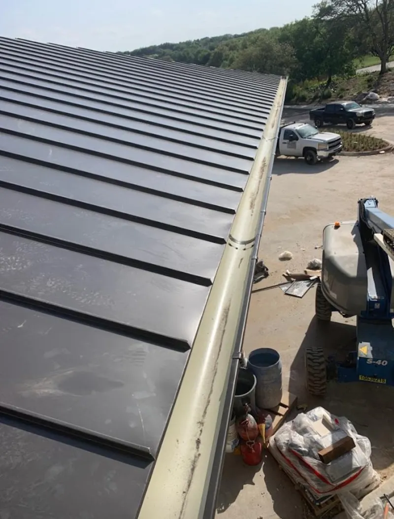 Standing seam panel and gutter detail on a metal roofing jobsite in Bluefield